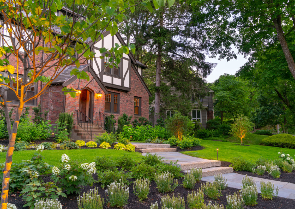 Front yard landscape design with stone steps, foundation planting, and landscape lighting at a home in Newton Massachusetts