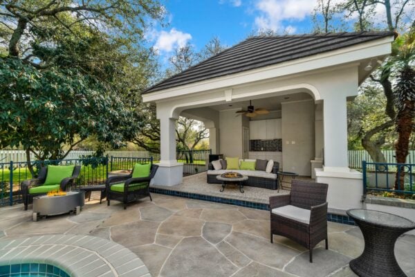 Luxury outdoor living space with a stone patio, built-in seating, and layered landscaping