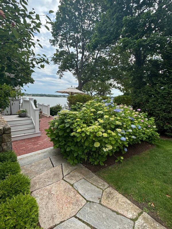 Custom patio design in Cohasset Massachusetts with balanced sun and shade Luxury outdoor living space designed by Land Design Associates in Cohasset Shaded patio area with pergola in Massachusetts Sunny backyard patio designed for outdoor entertaining Landscape architecture project featuring a custom patio in Cohasset Outdoor dining patio with shade structure in Massachusetts Landscape design incorporating patio placement and sun exposure