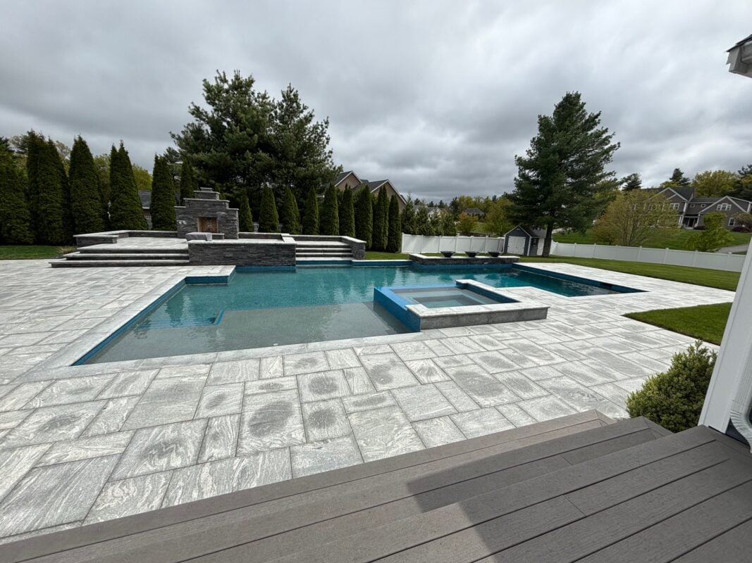 Luxury poolscape with gunite pool, stone decking, and integrated lighting in Massachusetts