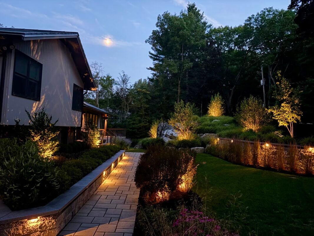 Landscape lighting design at dusk showing uplit trees and pathway lighting — Massachusetts exterior lighting cost guide