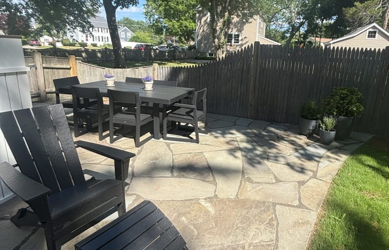 Custom bluestone patio with paver border installed by Land Design Associates in a Massachusetts backyard