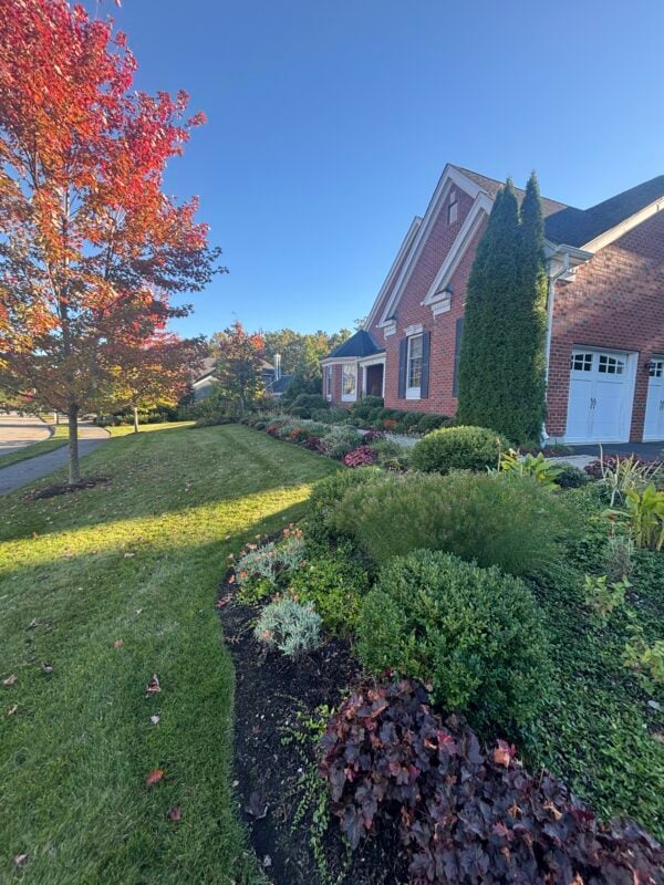 Low maintenance landscape design in New England with native perennials, ornamental grasses, a small lawn, and a stone path